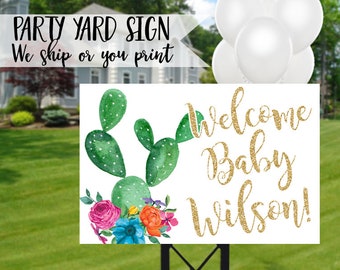 Puede incluir: Un cartel de bienvenida blanco con un cactus verde y flores coloridas. El texto en el cartel dice "¡Bienvenido bebé Wilson!" en purpurina dorada.