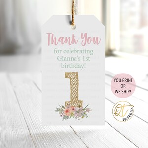 Peut inclure: Une &eacute;tiquette de remerciement rose et blanche avec des accents de paillettes dor&eacute;es. L'&eacute;tiquette dit "Merci de c&eacute;l&eacute;brer le 1er anniversaire de Gianna !" et pr&eacute;sente un grand num&eacute;ro un dor&eacute; avec des accents floraux. L'&eacute;tiquette comprend &eacute;galement le texte "VOUS IMPRIMEZ OU NOUS LIVRONS !" et un logo qui dit "DT PAPERIE."