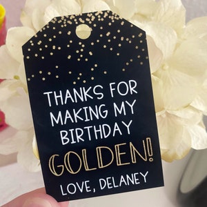 May include: Black and gold thank you tag with the text "Thanks for making my birthday golden! Love, Delaney".