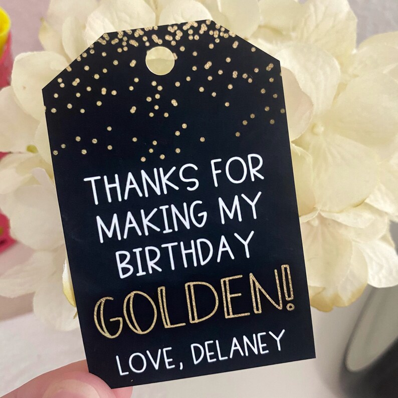 May include: Black and gold thank you tag with the text "Thanks for making my birthday golden! Love, Delaney".