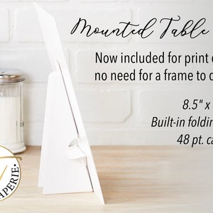 May include: White table sign with a built-in folding stand. The sign is 8.5 inches by 11 inches and is made of 48 pt. cardstock. The text on the sign reads "Mounted Table Sign" and "Now included for print orders - no need for a frame to display!"
