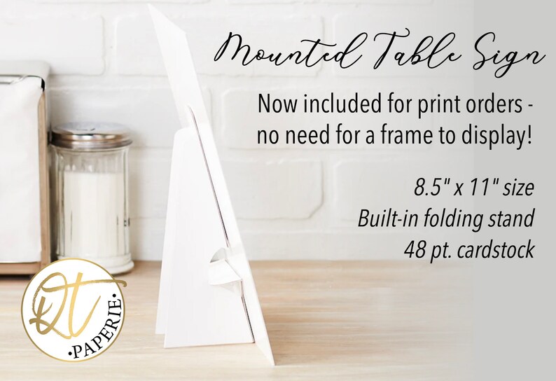 May include: White table sign with a built-in folding stand. The sign is 8.5 inches by 11 inches and is made of 48 pt. cardstock. The text on the sign reads "Mounted Table Sign" and "Now included for print orders - no need for a frame to display!"