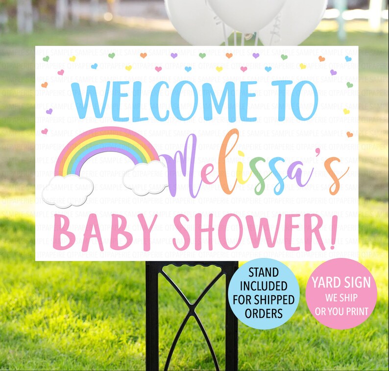 May include: A white yard sign with a rainbow, clouds, and the text "WELCOME TO Melissa's BABY SHOWER!" in colorful letters. The sign is decorated with small hearts.