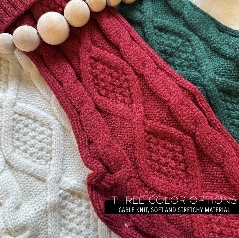 May include: Close-up of three cable-knit Christmas stockings in white, red, and green. The red stocking has a wooden bead garland. The text on the image reads "THREE COLOR OPTIONS, CABLE KNIT, SOFT AND STRETCHY MATERIAL."