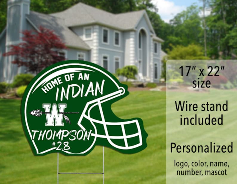 May include: Green and white personalized yard sign shaped like a football helmet. The sign says "Home of an Indian" with a letter W and the name Thompson and number 28. The sign is 17 inches by 22 inches and includes a wire stand.