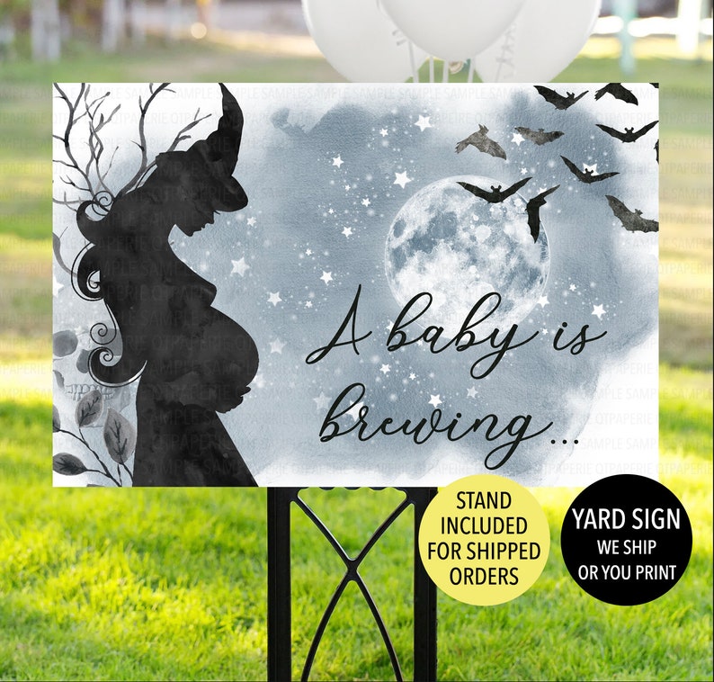 Op de afbeelding: Een blauw en wit bord voor in de tuin met een silhouet van een zwangere heks met een volle maan en vleermuizen op de achtergrond. De tekst op het bord luidt "A baby is brewing..."