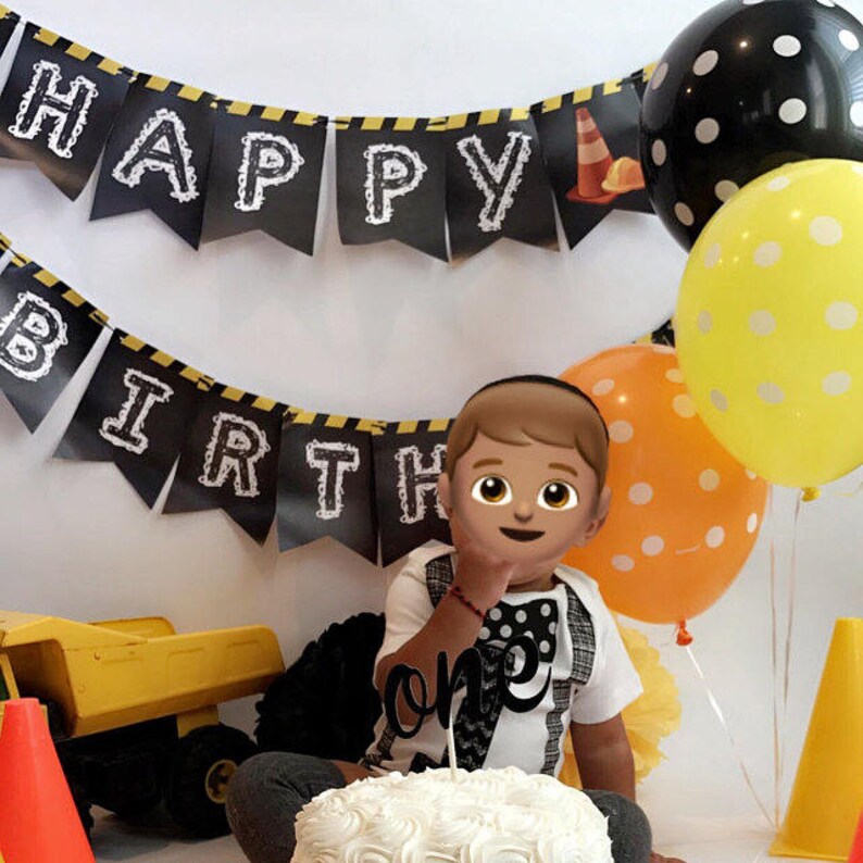 Puede incluir: Un ni&ntilde;o con una pajarita blanca y negra y una camisa blanca con texto negro que dice "uno" est&aacute; sentado frente a un pastel blanco con glaseado negro. El ni&ntilde;o sostiene un adorno de pastel "uno" blanco y negro. Hay globos negros y amarillos con tem&aacute;tica de construcci&oacute;n en el fondo. Una pancarta negra y amarilla que dice "Feliz cumplea&ntilde;os" est&aacute; colgada sobre el ni&ntilde;o.