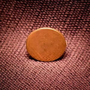 May include: A round, copper-colored button with a smooth surface.