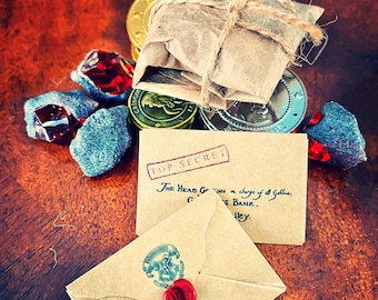 May include: A brown paper envelope with a red wax seal and the text "TOP SECRET" stamped on it. The envelope is on a wooden surface with a pile of gold coins and red and blue candy.