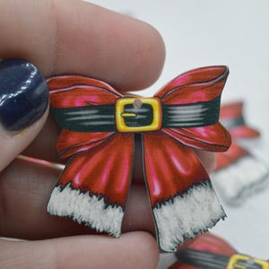 May include: Red and white wooden bow with a black belt and gold buckle. The bow has a white fur trim.