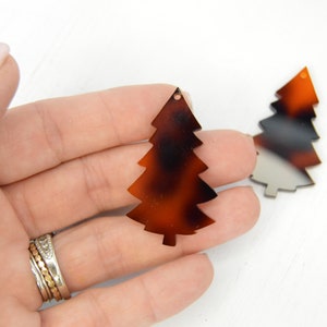 May include: Two brown and black tortoise shell Christmas tree shaped ornaments with a hole at the top for hanging.