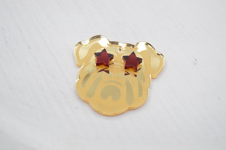 Pu&ograve; includere: Testa di bulldog in specchio dorato con occhi a forma di stella rossa.