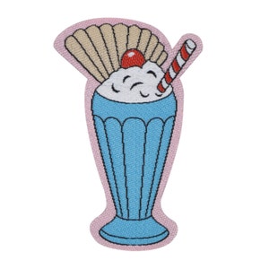 May include: An embroidered patch depicting a milkshake in a tall glass with a red cherry and a red and white striped straw. The milkshake is blue and white with a pink background.
