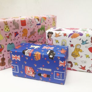 May include: Three gift boxes wrapped in colorful patterned paper. The top box is white with a floral pattern and features small illustrations of dolls and birds. The middle box is blue with a pattern of red hearts, British flags, and London landmarks. The bottom box is pink with a pattern of animals, toys, and other whimsical illustrations.