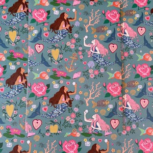 Peut inclure: Un motif de couleur sarcelle avec des sirènes, des poissons, des roses et des éléments floraux. Les sirènes ont des cheveux bruns et roses et des queues à motifs bleus et blancs. Le motif comprend des cœurs, des ancres et du corail.