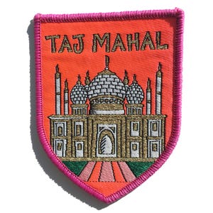Pode incluir: Um remendo bordado rosa e laranja com o Taj Mahal em dourado e branco. O remendo diz "TAJ MAHAL" em letras douradas.