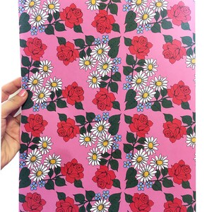 May include: Pink wrapping paper with a repeating pattern of red roses, white daisies, and blue forget-me-nots.