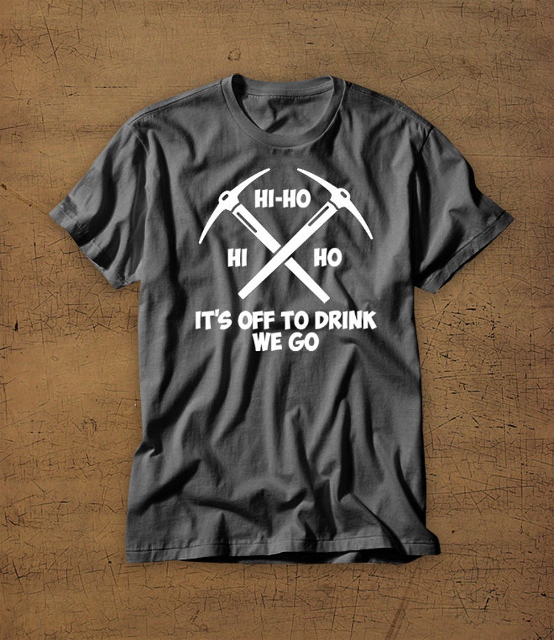 Puede incluir: Una camiseta gris oscuro con un gr&aacute;fico blanco de dos picos cruzados y el texto "Hi-Ho Hi Ho It's Off To Drink We Go".