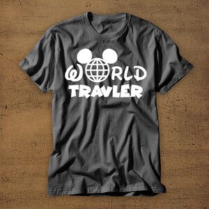 May include: A dark gray t-shirt with a white graphic of Mickey Mouse ears with a globe inside and the text "WORLD TRAVLER".