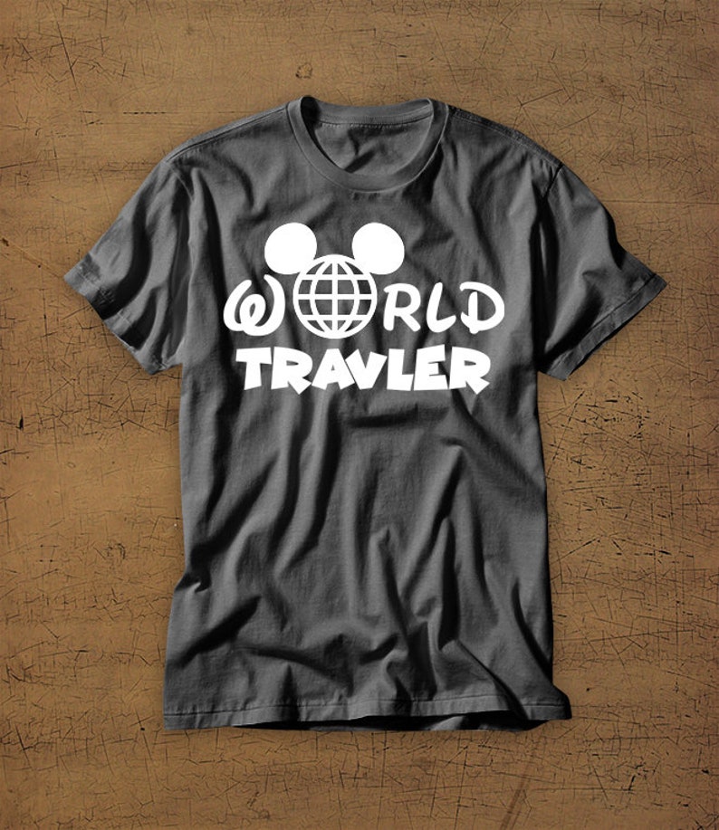 May include: A dark gray t-shirt with a white graphic of Mickey Mouse ears with a globe inside and the text "WORLD TRAVLER".