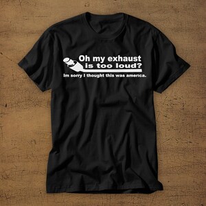 May include: Black t-shirt with a white graphic of a car exhaust pipe and the text "Oh my exhaust is too loud? Im sorry I thought this was america."