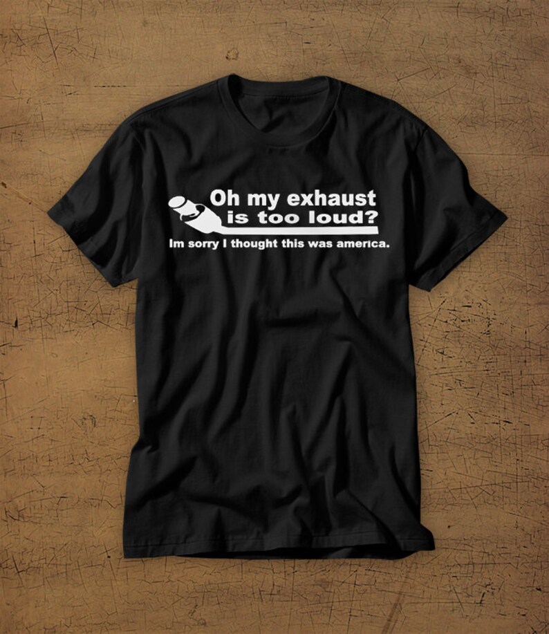 May include: Black t-shirt with a white graphic of a car exhaust pipe and the text "Oh my exhaust is too loud? Im sorry I thought this was america."