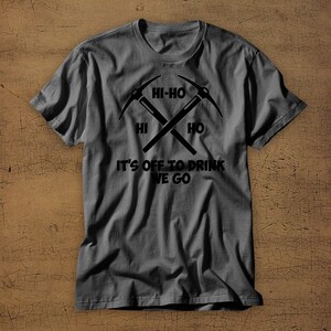 Puede incluir: Una camiseta gris oscuro con un gr&aacute;fico negro de dos picos cruzados. El gr&aacute;fico incluye el texto "Hi-Ho" y "It's off to drink we go".