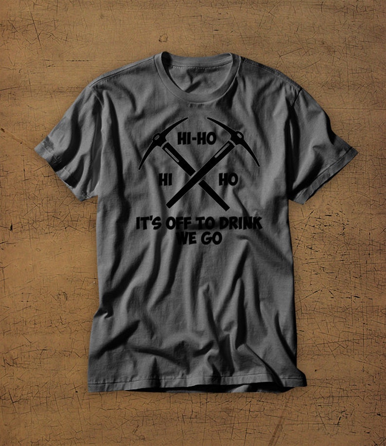 Puede incluir: Una camiseta gris oscuro con un gr&aacute;fico negro de dos picos cruzados. El gr&aacute;fico incluye el texto "Hi-Ho" y "It's off to drink we go".