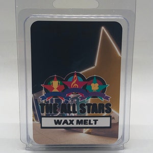 Puede incluir: Un derretido de cera en un envase de plástico transparente en forma de concha con un diseño de estrella dorada y el texto "THE ALL STARS WAX MELT".