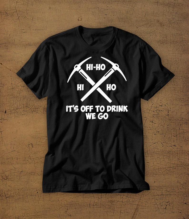 Puede incluir: Camiseta negra con un gr&aacute;fico blanco de dos picos cruzados y el texto "Hi-Ho Hi Ho It's Off To Drink We Go".