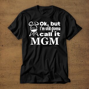 May include: Black t-shirt with white text that reads "Ok, but I'm still gonna call it MGM" with a grill graphic.