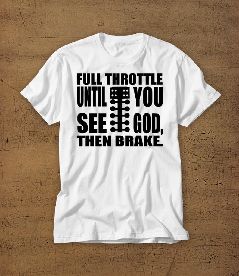 May include: White t-shirt with black text that reads "Full Throttle Until You See God, Then Brake."  The text includes a graphic of a drag racing Christmas tree.