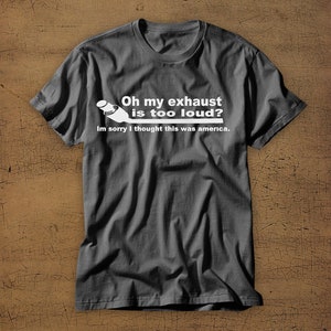 May include: A dark gray t-shirt with a white graphic of a car exhaust pipe and the text "Oh my exhaust is too loud? Im sorry I thought this was america."