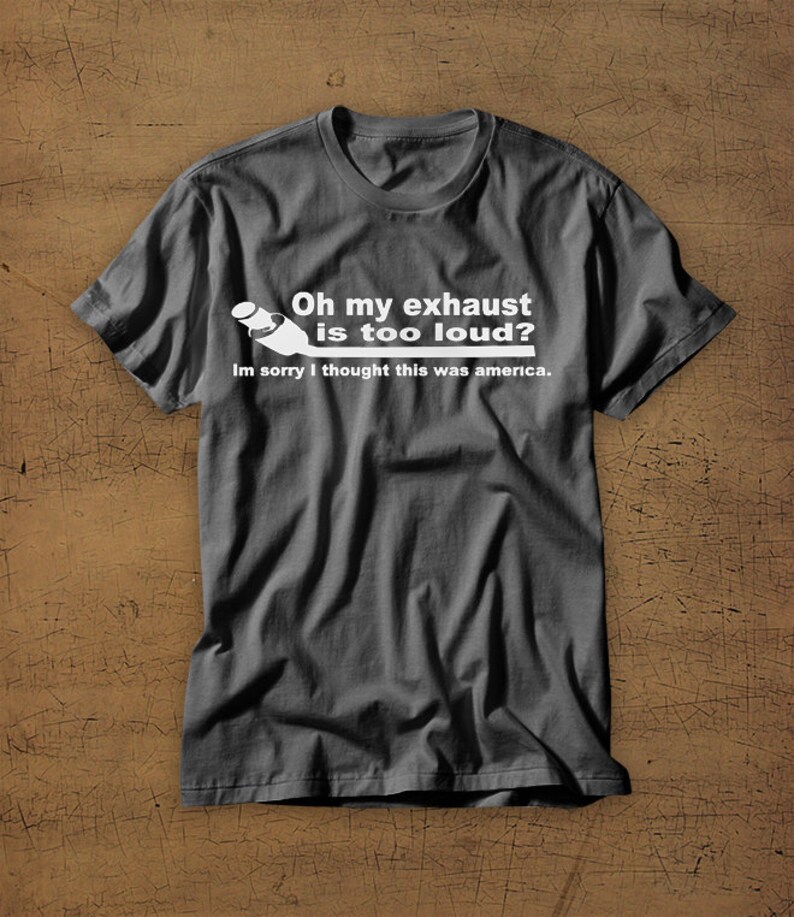 May include: A dark gray t-shirt with a white graphic of a car exhaust pipe and the text "Oh my exhaust is too loud? Im sorry I thought this was america."
