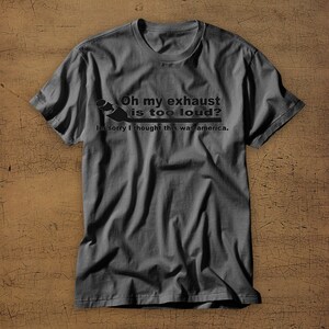 May include: A dark gray t-shirt with a humorous saying about a loud exhaust. The text reads "Oh my exhaust is too loud? Im sorry I thought this was america."