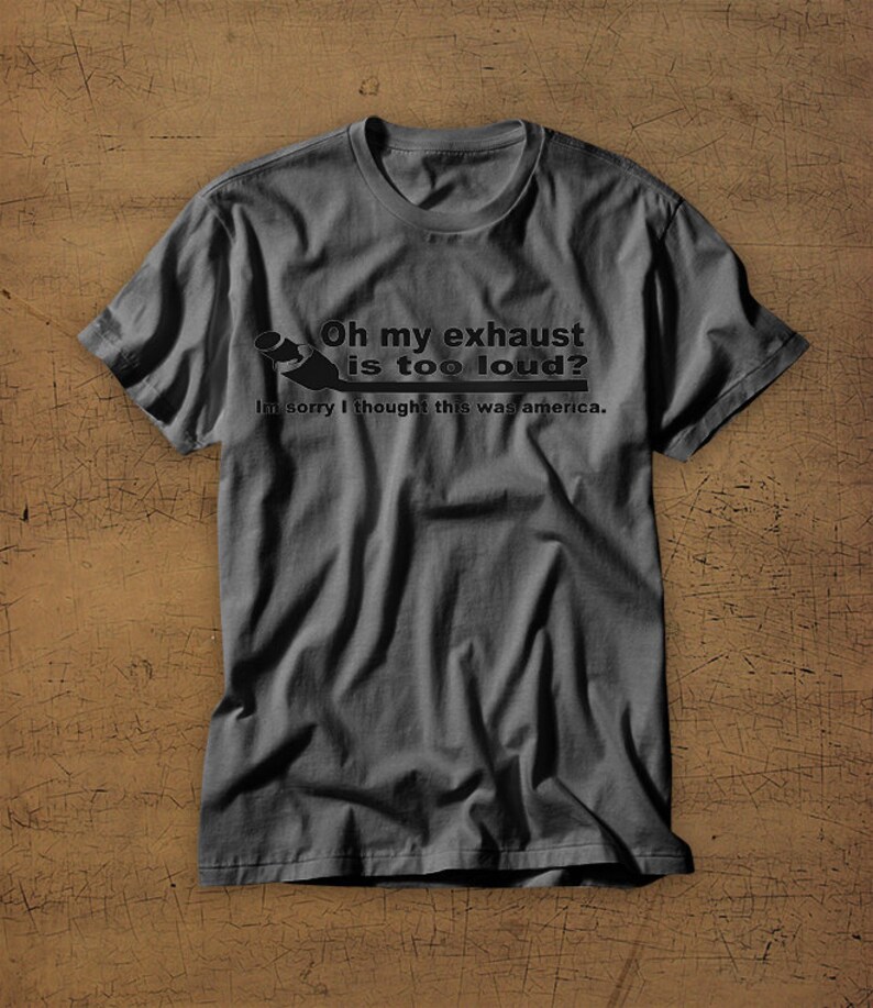 May include: A dark gray t-shirt with a humorous saying about a loud exhaust. The text reads "Oh my exhaust is too loud? Im sorry I thought this was america."