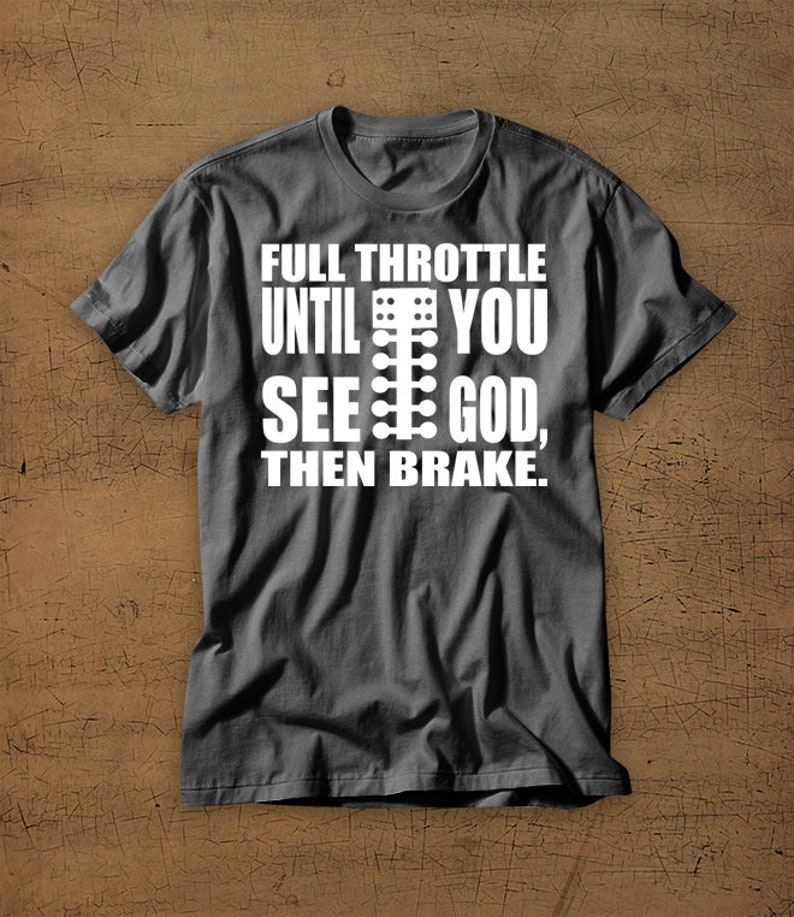 May include: A dark grey t-shirt with a white graphic that reads "Full Throttle Until You See God, Then Brake." The graphic also includes a white silhouette of a drag racing Christmas tree.