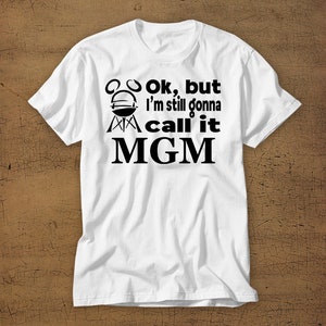 May include: White t-shirt with black text that reads "Ok, but I'm still gonna call it MGM" with a grill graphic above the text.