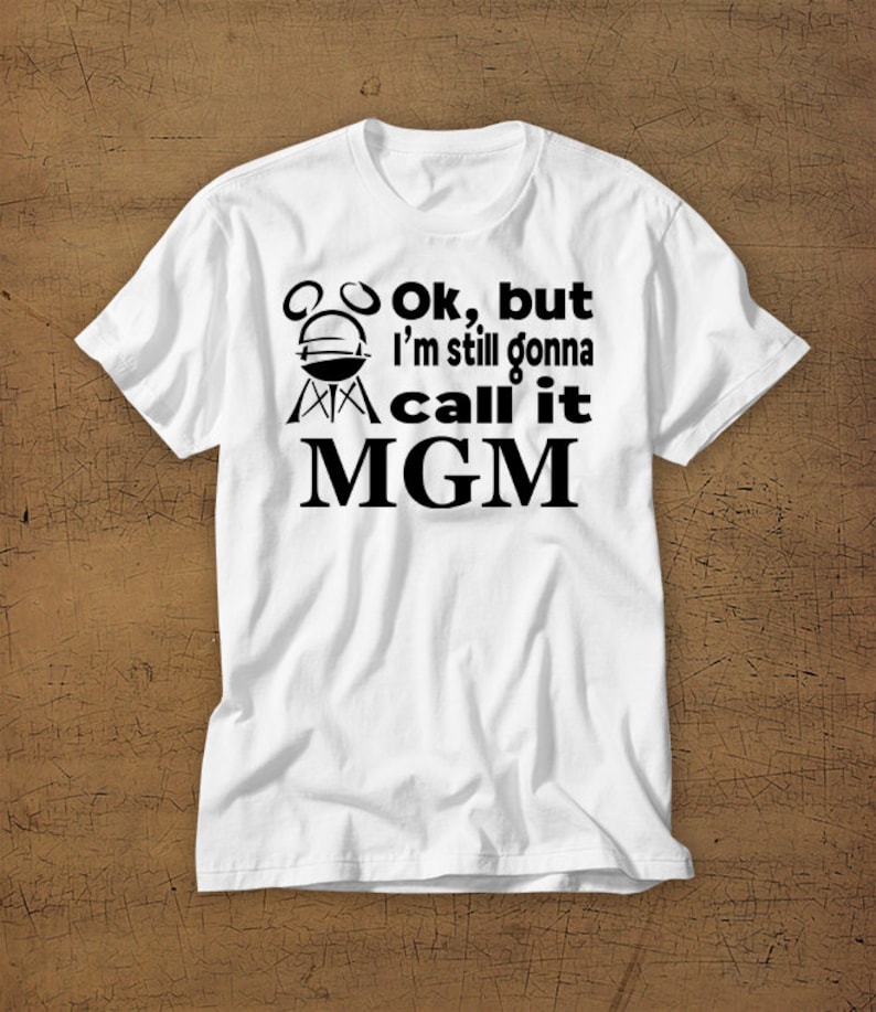 May include: White t-shirt with black text that reads "Ok, but I'm still gonna call it MGM" with a grill graphic above the text.