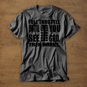 May include: A dark grey t-shirt with a black graphic print that reads "Full Throttle Until You See God, Then Brake". The graphic includes a black and white illustration of a drag racing Christmas tree.