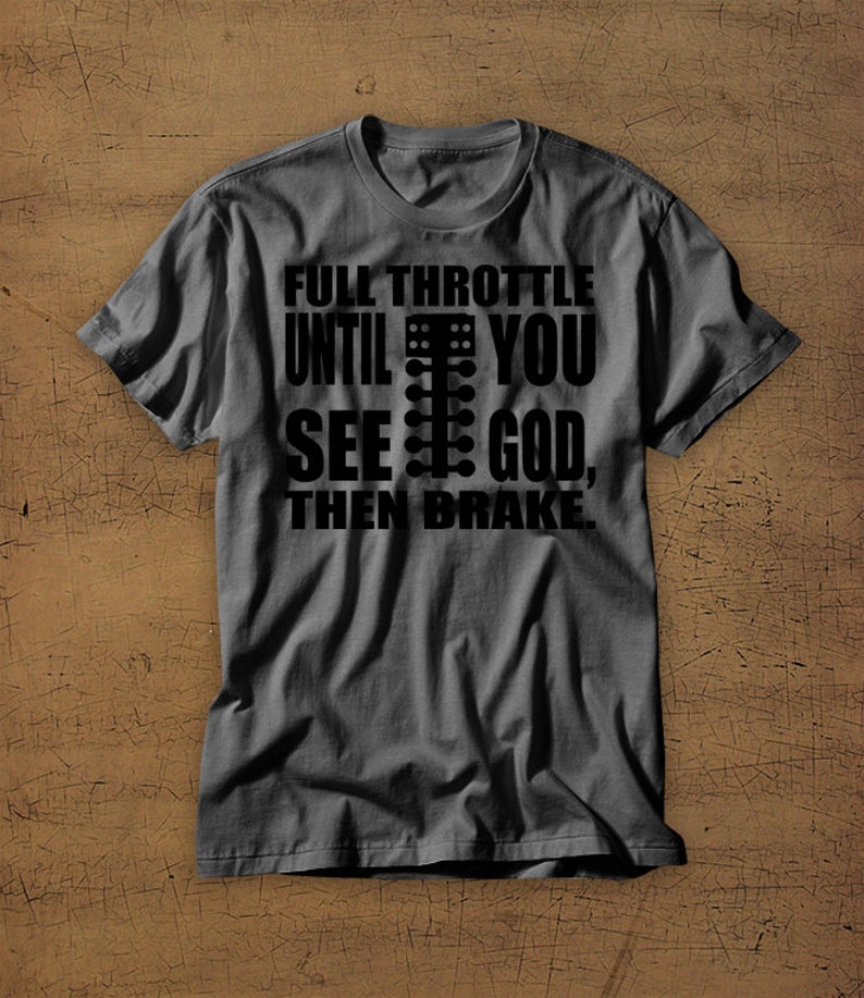 May include: A dark grey t-shirt with a black graphic print that reads "Full Throttle Until You See God, Then Brake". The graphic includes a black and white illustration of a drag racing Christmas tree.