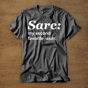 May include: A dark grey t-shirt with white text that reads "Sarc: my second favourite -asm."