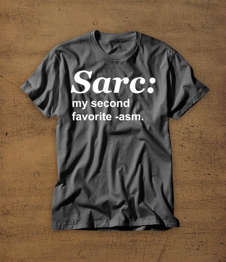 May include: A dark grey t-shirt with white text that reads "Sarc: my second favourite -asm."