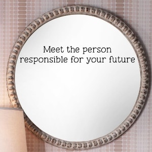 May include: A white round mirror with a decorative beaded frame. The mirror has the text "Meet the person responsible for your future" written on it.