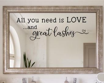 May include: A silver framed mirror with the text "All you need is LOVE...and great lashes" with a small heart symbol.