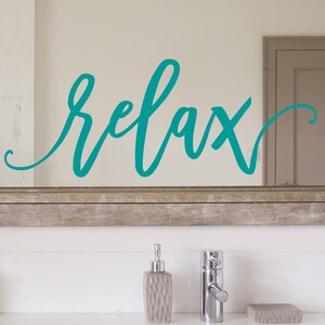 May include: A bathroom mirror with a teal "relax" sign on the glass. The mirror has a wooden frame.