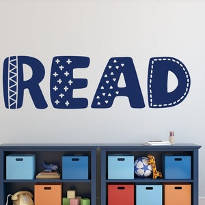 May include: Blue and white wall decal with the word "READ" in a playful, patterned font. The decal is on a white wall above a blue bookshelf with colourful storage bins.