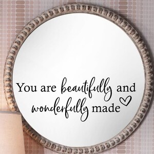 Op de afbeelding: Een ronde witte spiegel met een parelrand en de tekst "You are beautifully and wonderfully made" met een klein hartje.