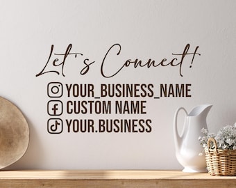 May include: A wall decal with the text "Let's Connect!" in brown script, along with social media icons and placeholders for usernames. A white pitcher and a small basket of flowers sit on a wooden surface.