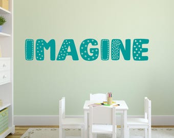 Puede incluir: Pegatina de pared azul turquesa con la palabra "IMAGINE" en una fuente divertida y con patrones. La pegatina está en una pared verde claro en una habitación con muebles blancos.